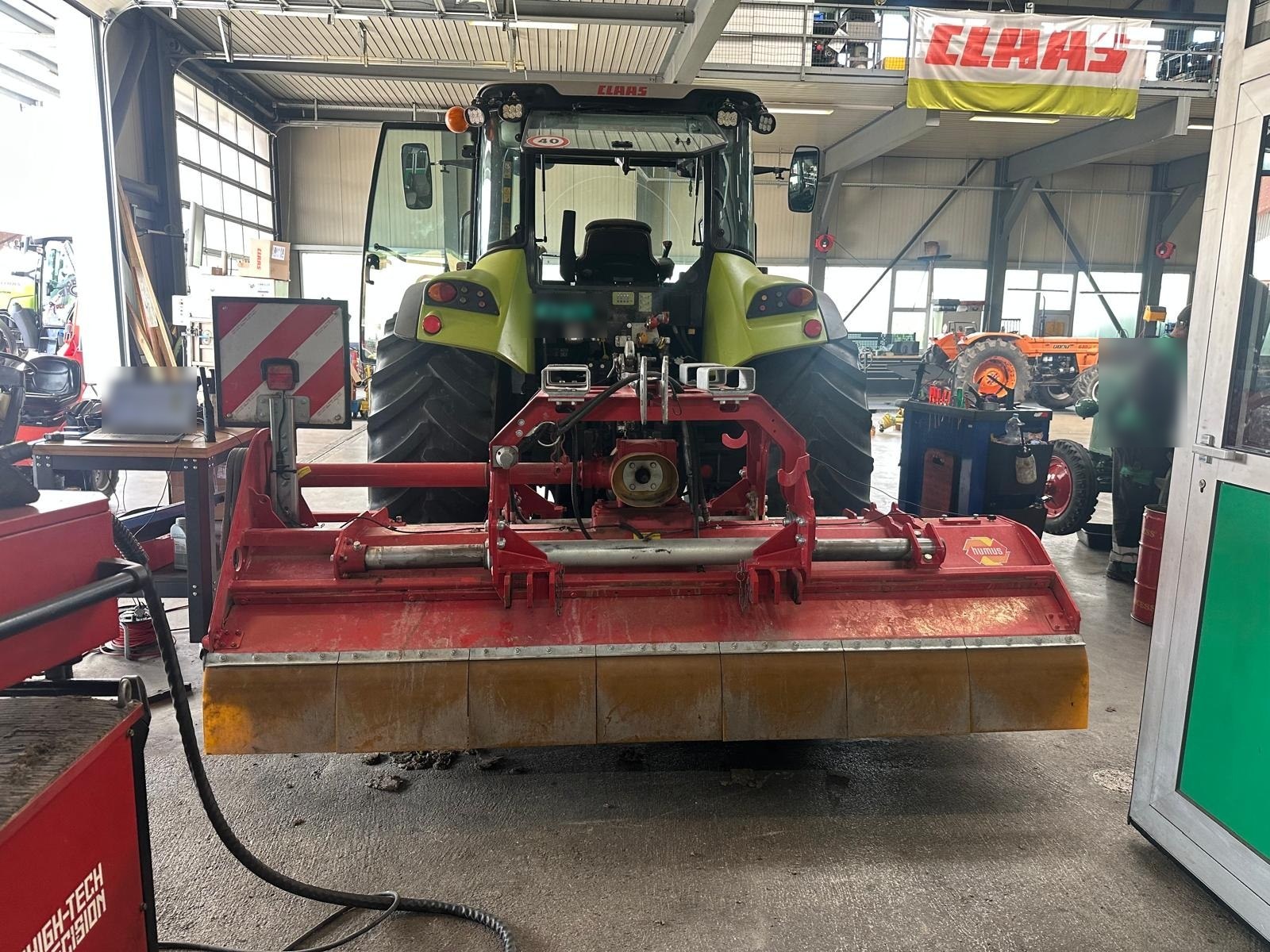 Triturador de martelos montado em um trator em uma oficina agrícola, pronto para o balanceamento